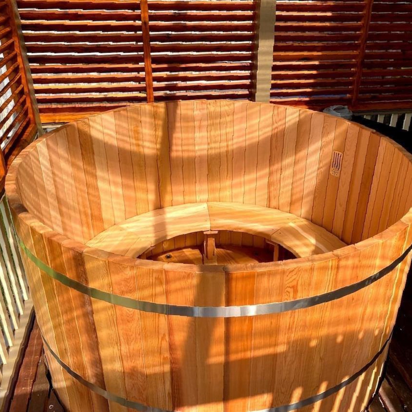 Wooden hot tub on a deck with wooden slats in the background