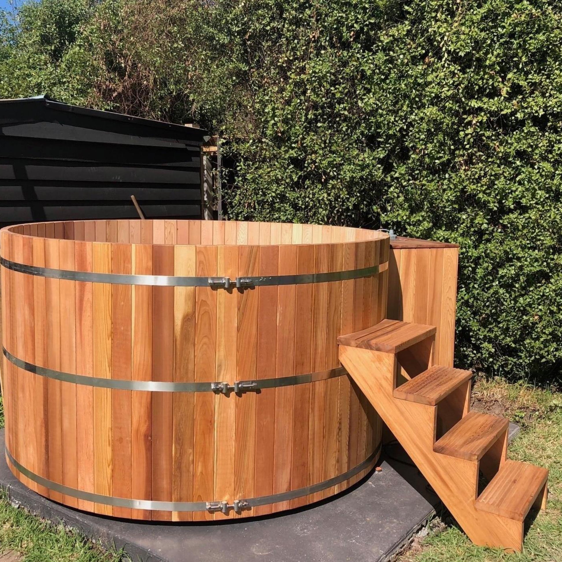 Wooden hot tub with steps in a garden setting