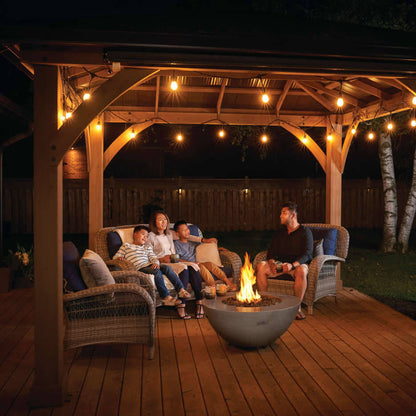 Family gathered around a fire pit under a wooden pergola at night.