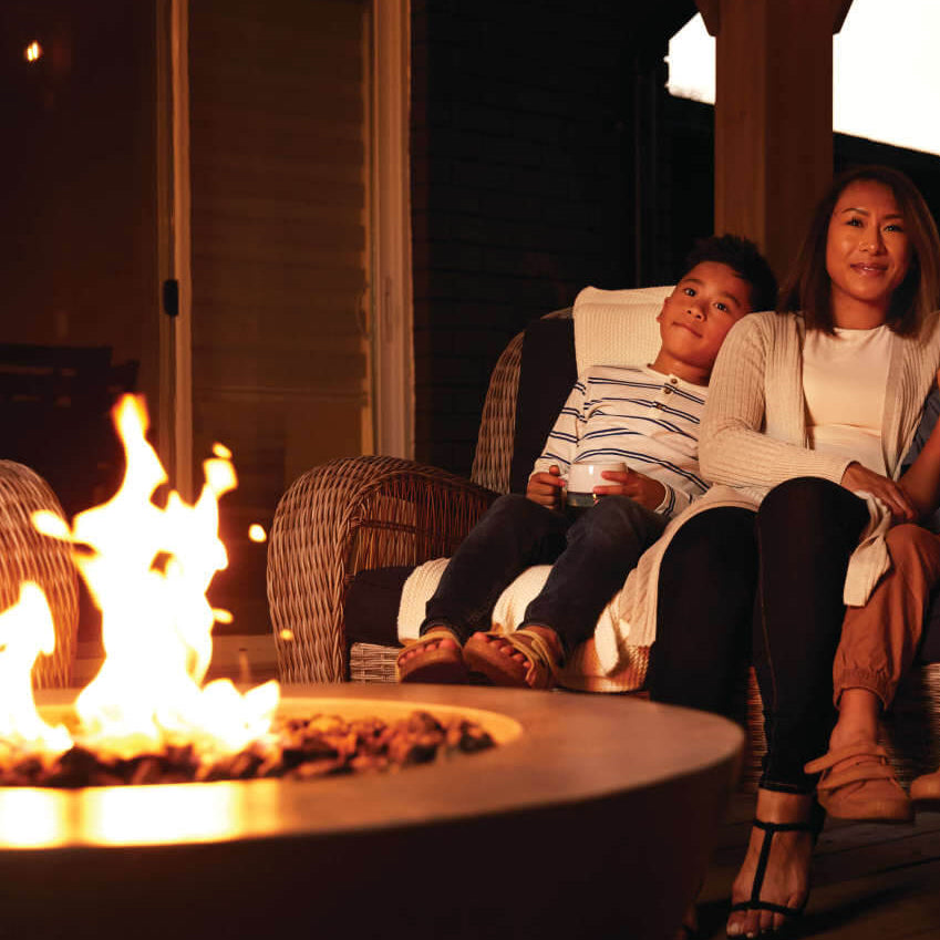 Family sitting on a couch by a fire pit at night